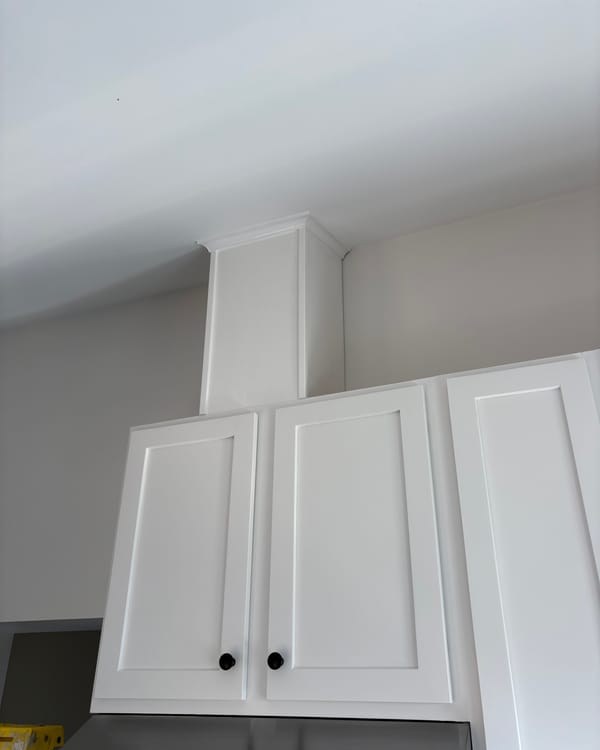 Boxed in range hood and upper cabinets painted white