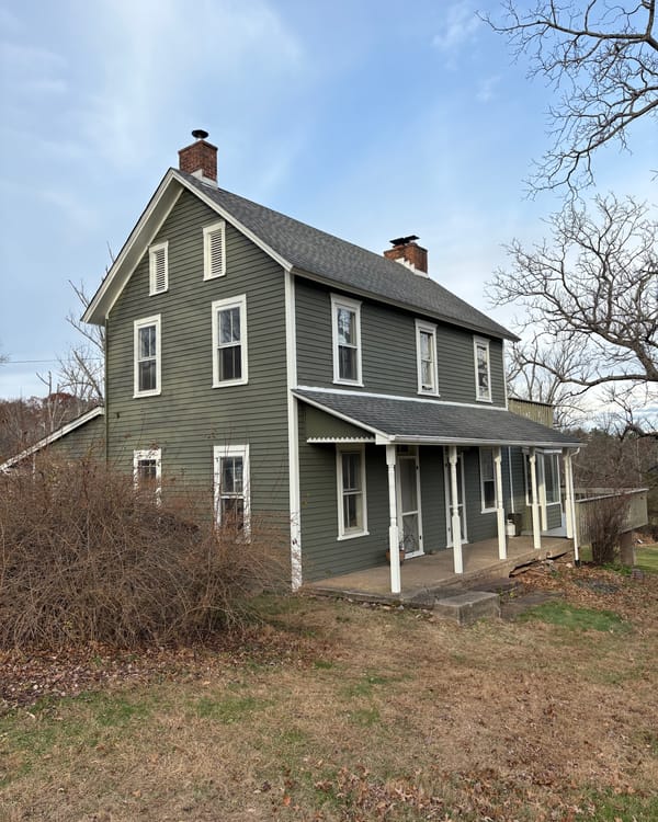 Farmhouse with green siding and white trim after painting