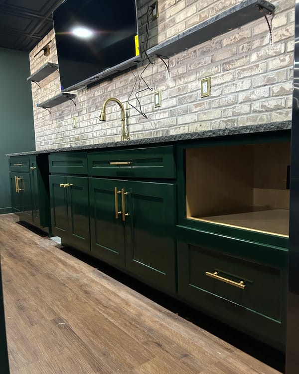 Basement bar cabinets refinished in dark green with brass pulls