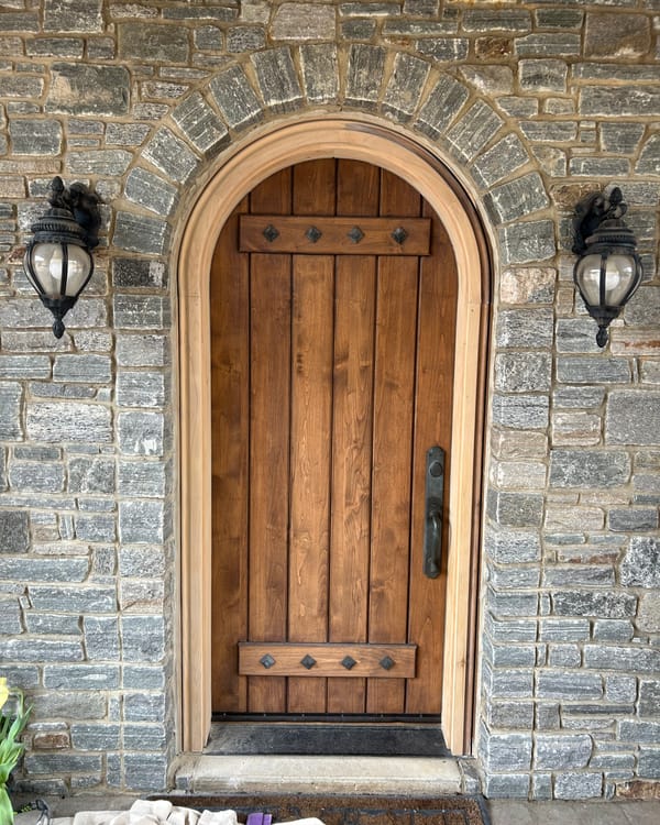 Arched wood front door in a stone wall