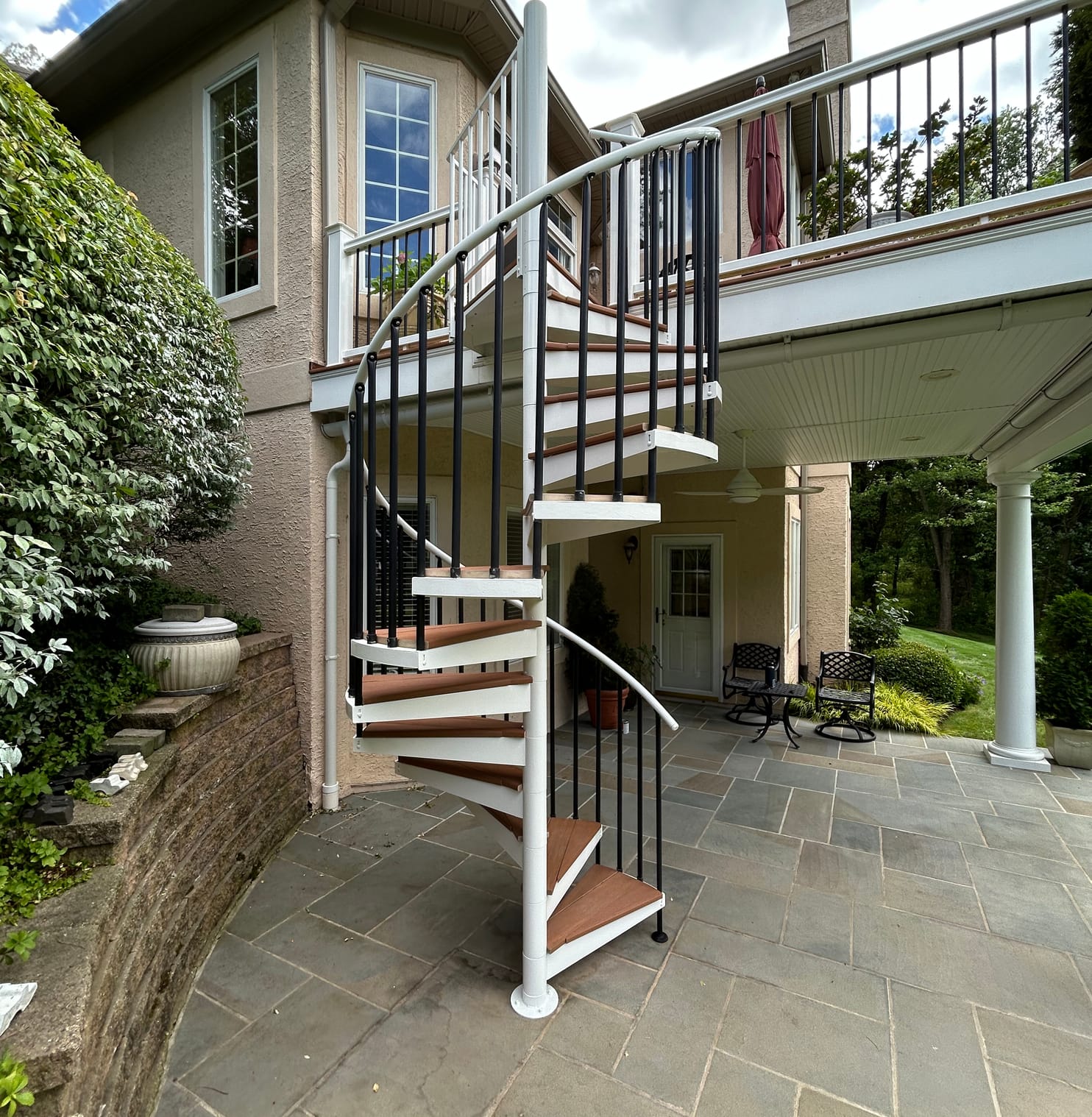 The finished white spiral staircase over a stone patio