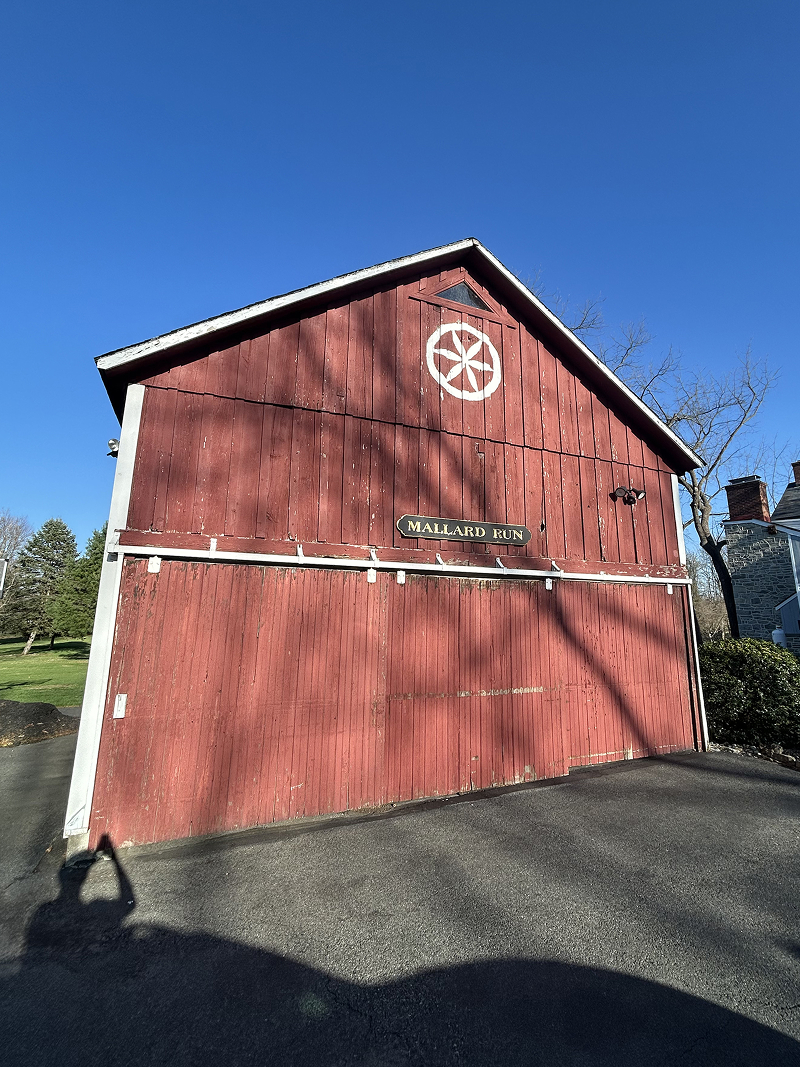 Exterior wood doors after staining — rich walnut finish on stone carriage house