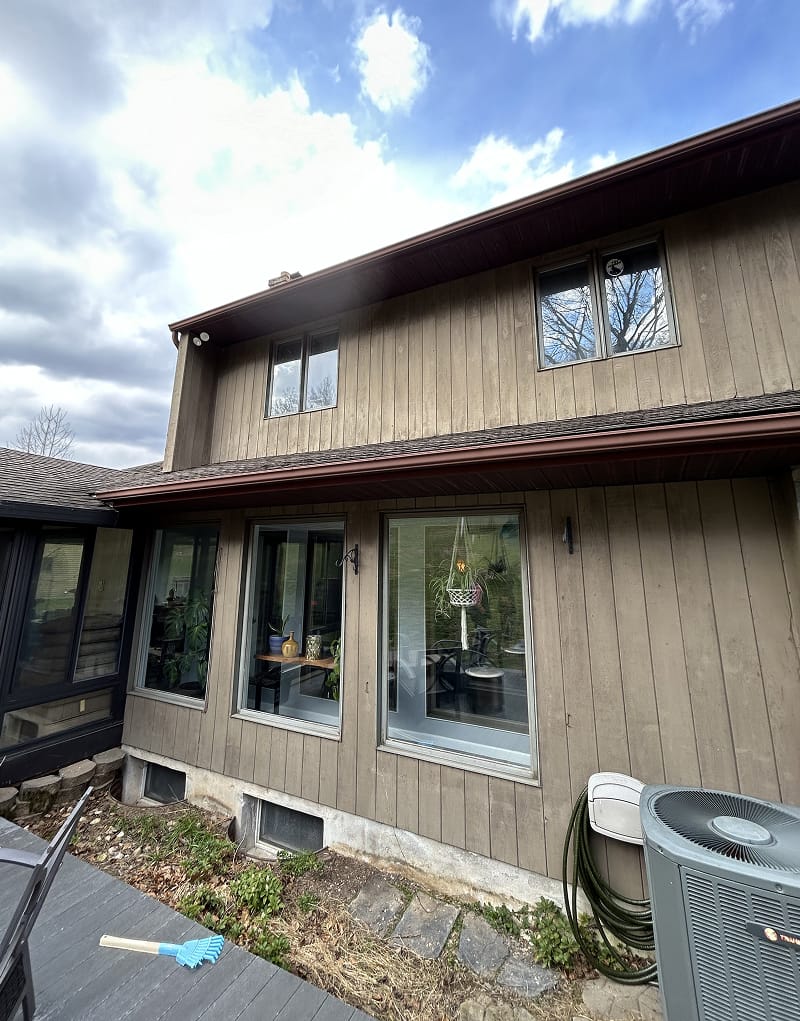 Exterior wood doors after staining — rich walnut finish on stone carriage house
